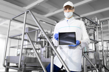 man in a white robe and a mask with a tablet in his hands is at the factory
