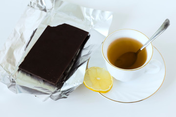 a Cup of tea in a white Cup and a bitten bar of dark chocolate