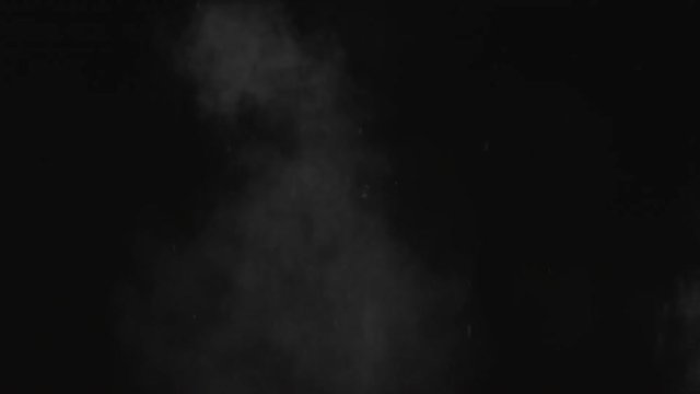 Dusty bullet hit on a wall with chunks of debris flying out. White powder explosion on black background.Impact  dust particles. Dust explosion in front of black background, slow-motion close up.