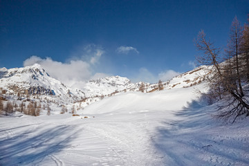 Fototapeta na wymiar Panoramic view of the sunny snow-covered landscape of the Alpe Sangiatto above the Alpe Devero in Piedmont, Italy.