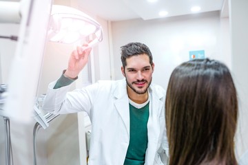 Obraz premium Male dentist adjust searchlight before starting work