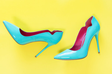 Pair of Blue high heels glassy shoes on yellow background, top view