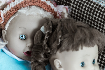 Creepy dolls. Demonic doll with one bright eye peeks out from behind the shoulder of another doll