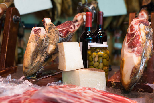 Still life of spanish pork jammon on holder, bottles of wine cheese and olives
