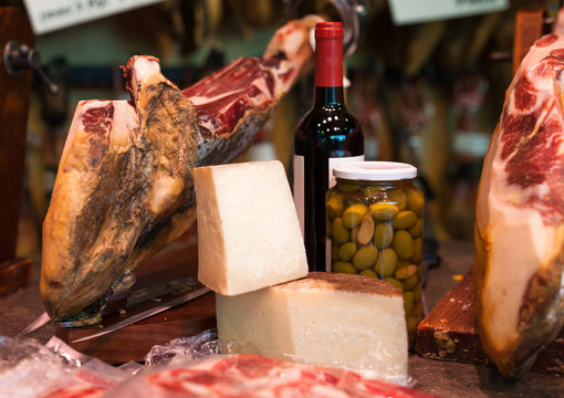 Still life of spanish pork jammon on holder, bottles of wine cheese and olives