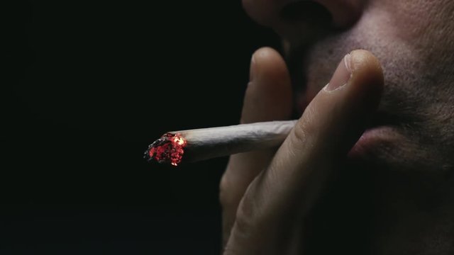 Dar una calada a un cigarro de liar o canuto y soltar el humo