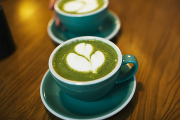 Obraz na płótnie Canvas Green tea matcha latte at a coffee shop cafe on wooden table