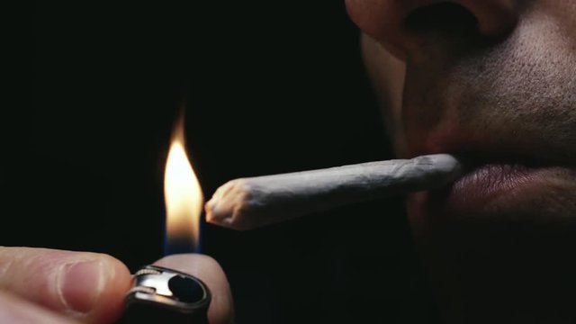 Encender cigarrillo liado o canuto con mechero y primera calada