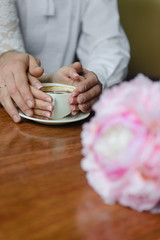 Fototapeta na wymiar Couple, happiness, family. Hands of happy couple and cup of fragrant coffee
