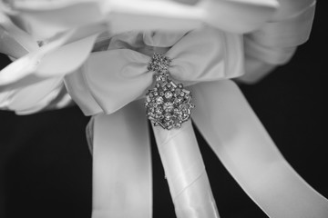 bouquet details showing white ribbon and jewellery at a wedding