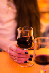 A glass of red wine in the hand of a young girl