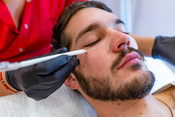 Happy male patient with correction lines on the face in an examination room.