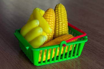 Small basket with artificial bananas and corn. Child Shopping Concept