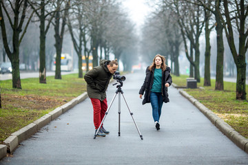 on the wolkway in town a guy takes a picture of a young girl of outdor