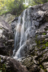 Fototapeta na wymiar Vertical waterfall in rocks. Mountain river in mountains.
