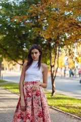 portrait of a young beautiful brunette woman on the street, model posing, women's urban street fashion, warm colors