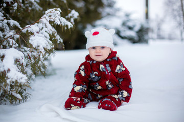 Fototapeta na wymiar Little cute smiling baby boy, sitting outdoors in the snow