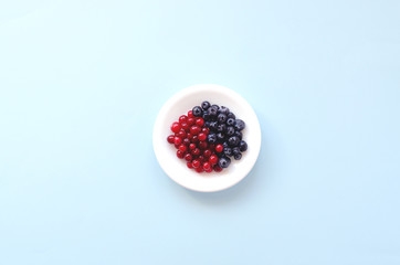 White saucer with berries on a blue background.
