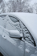 Car covered by snow in winter season. Side view in selective focus.