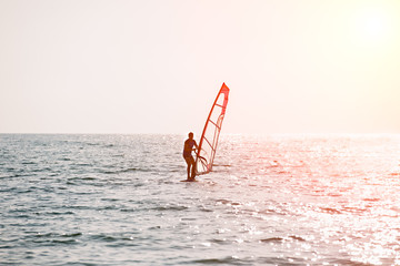 Surfer riding waves in a beautiful sunny day. Young man enjoying the wind and the ocean surfing.