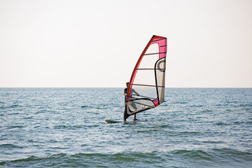 Surfer riding waves in a beautiful sunny day. Young man enjoying the wind and the ocean surfing.