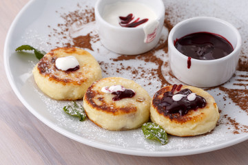 Obraz na płótnie Canvas Cheese pancakes with currant jam and sour cream on plate.