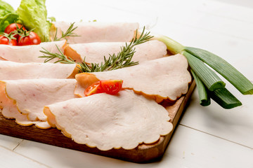 Fette di tacchino su tagliere di legno con verdure, fuoco selettivo