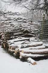 Pile of firewood covered by snow in the garden in winter season.