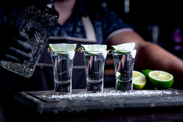 aperitif with friends in the bar, three glasses of alcohol with lime and salt for decoration. Tequila shots, selective focus