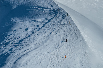 Obraz premium Free ride skiers, skiing down steep slope, good background with white valley and mountains in french alps. Winter sport concept with adventure guys on mountain top hiking to start point.