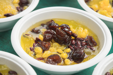 Thai dessert mix with clear jelly, red bean, dried monkey apple and another sweet thing put together in syrup in bowls in pattern - close up