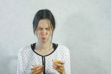 Emotions from the sour on the girl's face. Brunette woman eating sour tangerine and wincing.