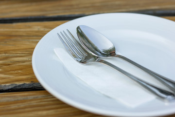 fork and spoon with white plate on wood table