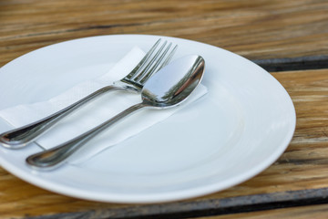 fork and spoon with white plate on wood table