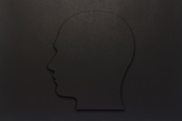 Black cardboard head on a black background. Copy space. Flat lay, top view.