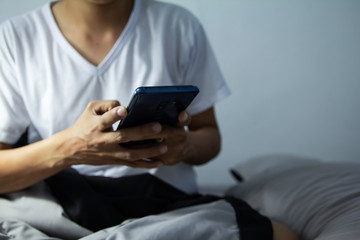 Young man sitting on the bed using smartphone at late night, Phone disease and Nomophobia. Healthy Concept