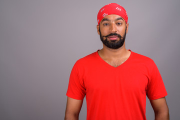 Portrait of young handsome Indian man wearing red shirt