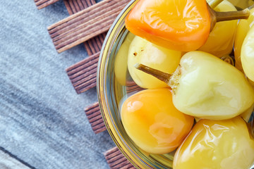 Pickled preserved bell peppers in glass bowl on wooden background