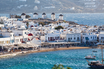panoramic view of the Mykonos town harbor with famous windmills from the above hills on a sunny summer day, Mykonos, Cyclades, Greece - obrazy, fototapety, plakaty