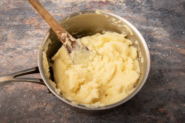 Pan of mashed potato with wooden spoon
