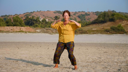 Senior woman practicing taiji gymnastic at sandy beach