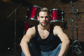 Beat of drums. Rock star or rocker. Enjoying instrumental music. Handsome man sit on stage at...