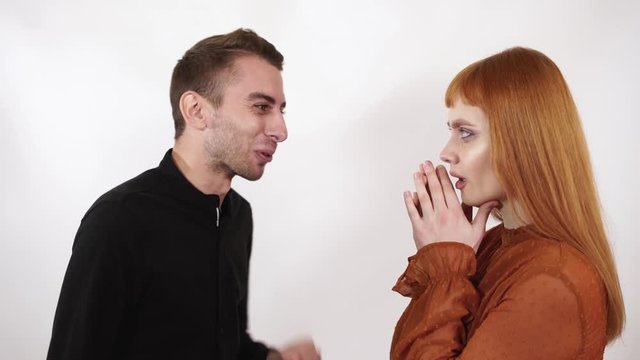 Angry agressive man yelling at his beautiful girlfriend with long red hair. Woman close her face and ears, she can not listen this bad words.