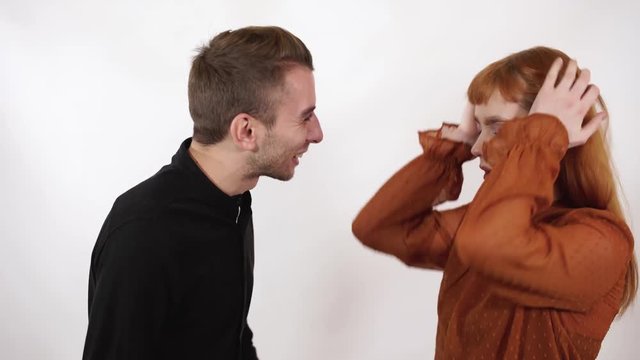 Angry agressive man yelling at his beautiful girlfriend with long red hair. Woman close her face and ears, she can not listen this bad words.