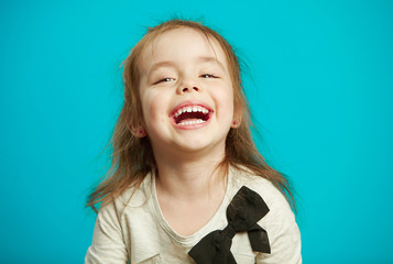 cheerful little girl laughs on blue background.