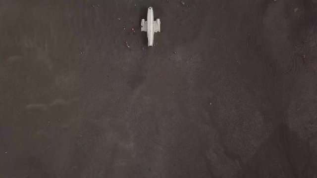 Drone shot: Airplane crashed on black sand beach in Iceland, DC3 navy plane laying on sand. aerial view