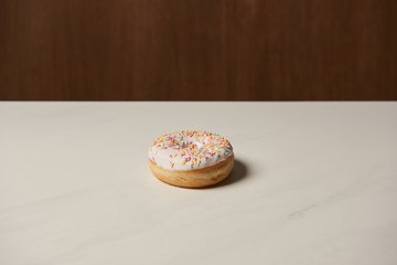 sweet glazed donut with sprinkles on white table