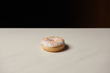 sweet donut on white table isolated on black