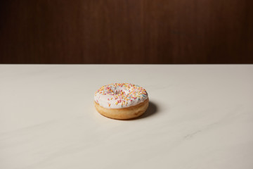 tasty glazed doughnut with sprinkles on white table