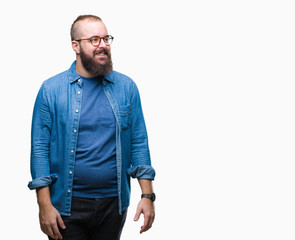 Young caucasian hipster man wearing glasses over isolated background looking away to side with...